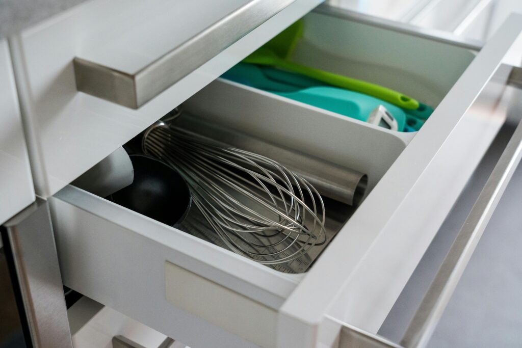 Open kitchen drawer showcasing organized utensils including a whisk and scoop.