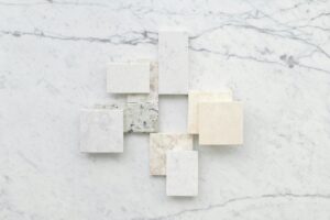 Aesthetic flatlay of diverse marble tiles on a light stone background for design inspiration.