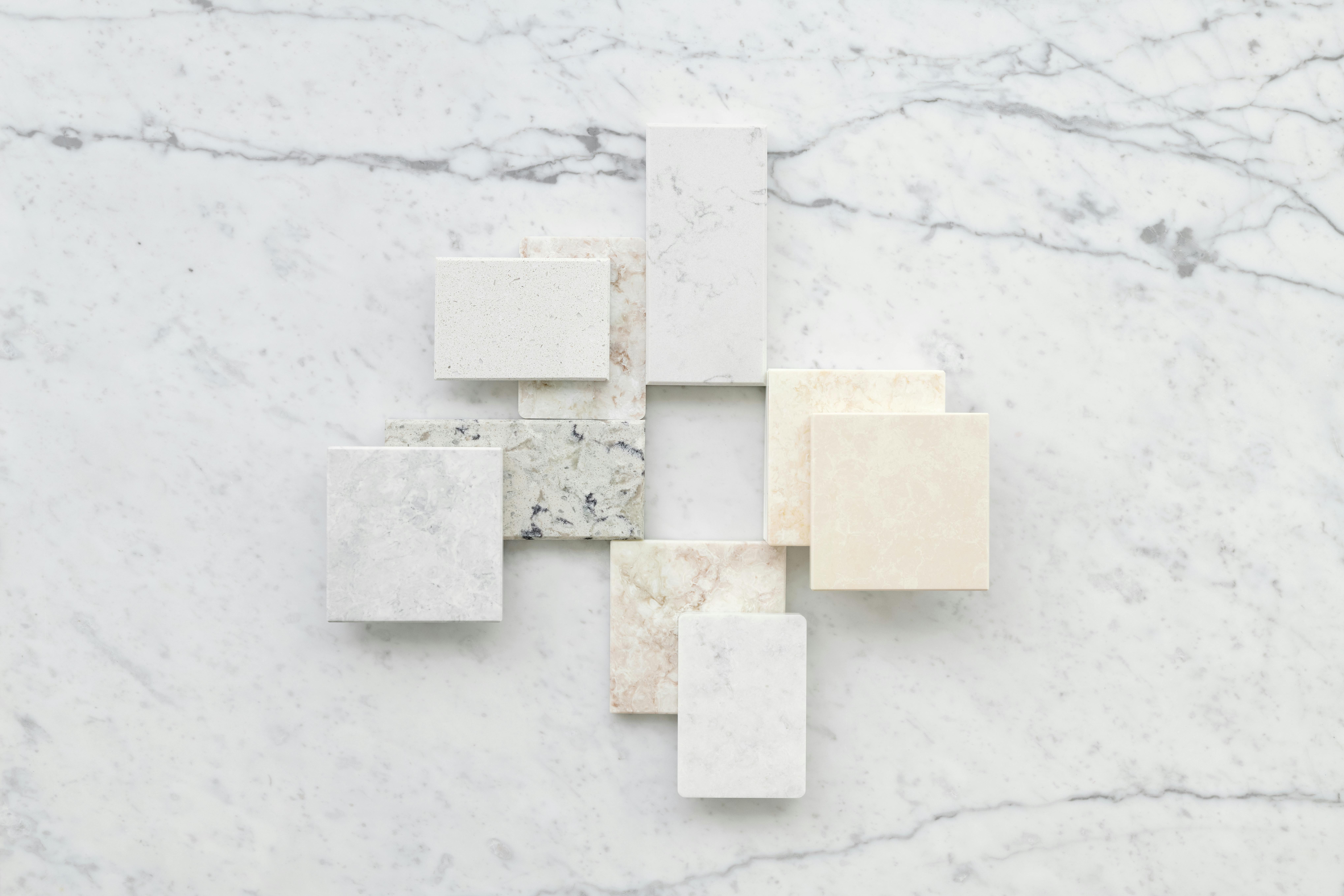 Aesthetic flatlay of diverse marble tiles on a light stone background for design inspiration.